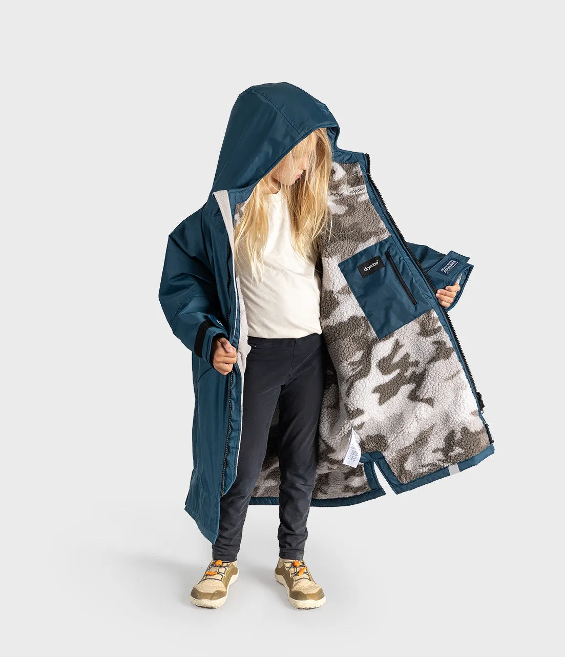 A child wearing a long navy hooded Dryrobe with a gray and white camouflage sherpa lining, shown against a light gray studio background.